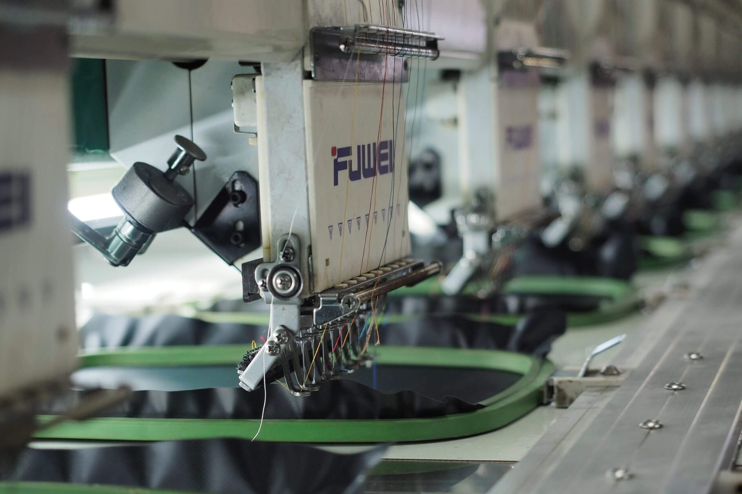 A row of machines in a factory with green fabric.