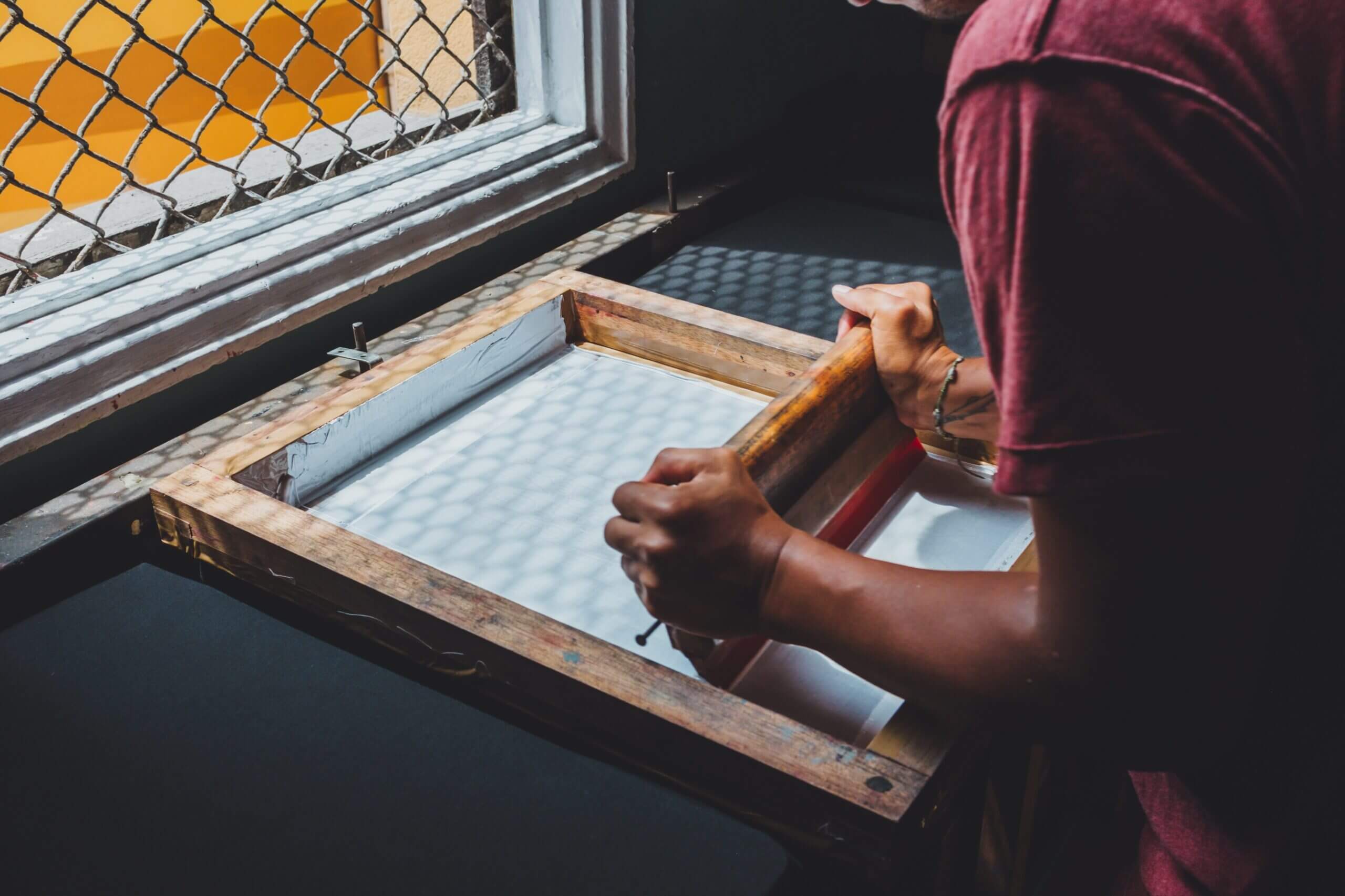A person is working on an object in front of a window.