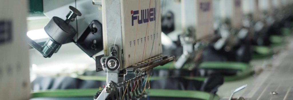 A row of machines in a factory with green fabric.